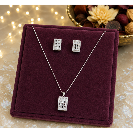 Silver geometric rectangular pendant necklace with matching crystal stud earrings displayed on a luxurious plum velvet frame over a premium pearlized surface with softly blurred fairy lights and decorative potpourri.