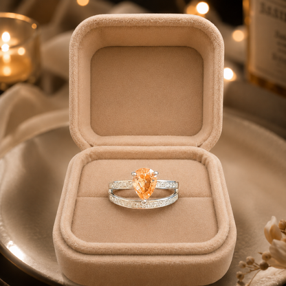 Silver split-band ring with a pear-cut peach crystal stone and shimmering micro-crystal detailing by TIAS Collection.