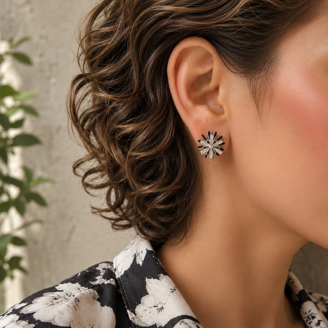 Woman wearing rotating silver and black floral spinner stud earrings with black and ivory floral linen shirt.