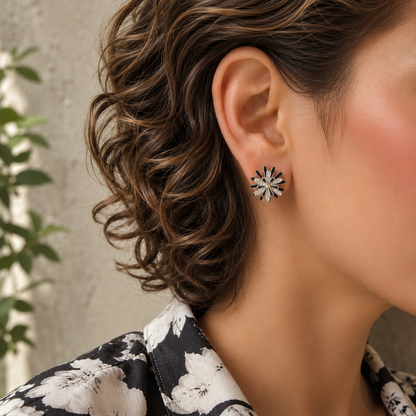 Woman wearing rotating silver and black floral spinner stud earrings with black and ivory floral linen shirt.