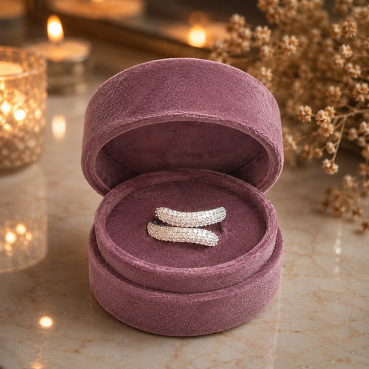 Silver twisted pavé wrap ring with shimmering micro-set stones displayed in a premium mauve velvet jewellery box on a luxury marble surface