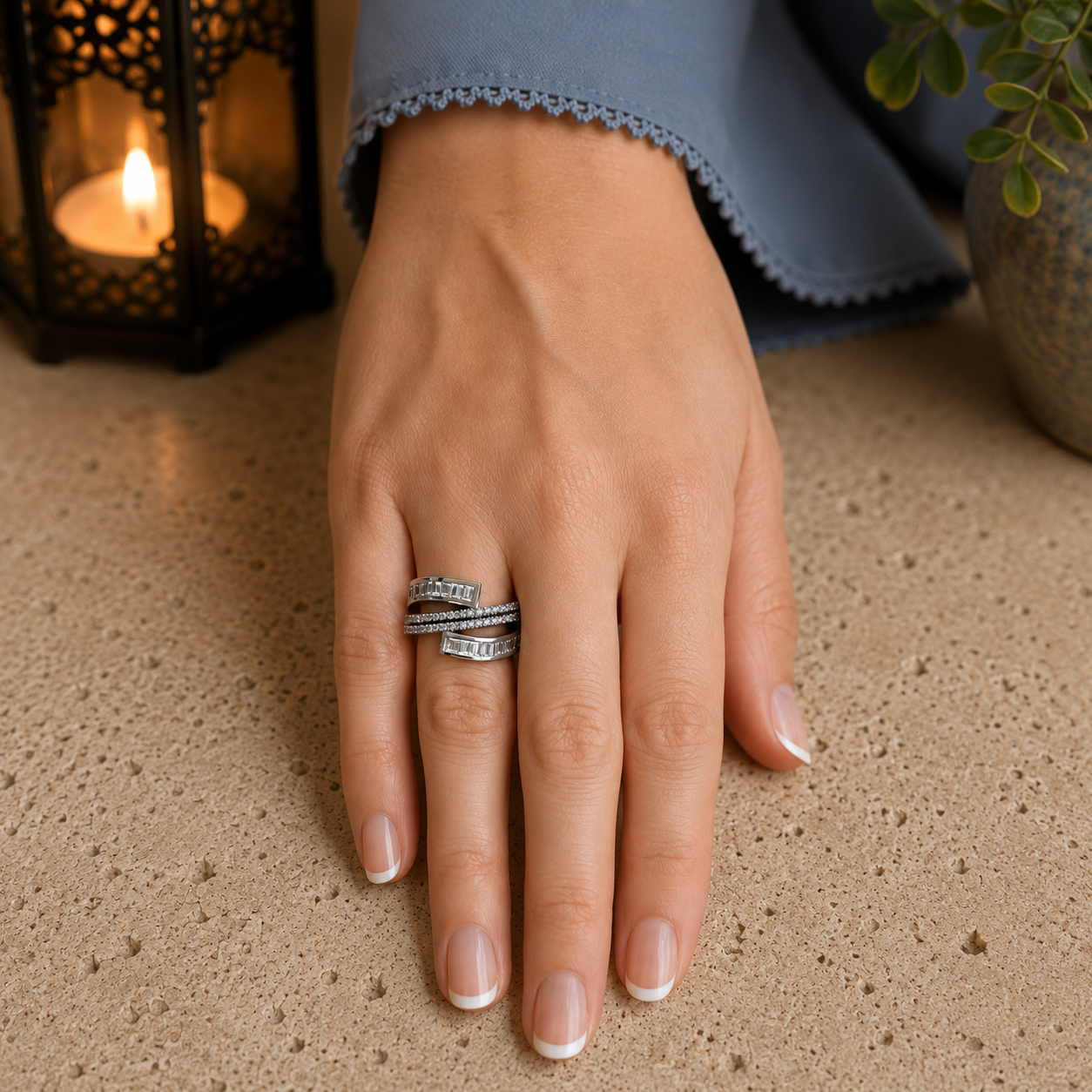 Elegant silver sculpted multi-band crystal statement ring worn on a hand with a refined bluish-grey sleeve in a luxury lifestyle setting.