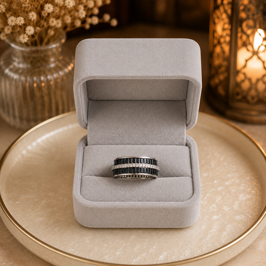 Wide interwoven crystal statement band ring displayed in a premium light grey velvet jewellery box on a pearlized cream tray with warm ambient lantern lighting.