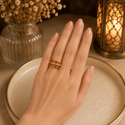 Model wearing a wide interwoven crystal band ring with sparkling zircon detailing on a manicured hand against a warm luxury setting
