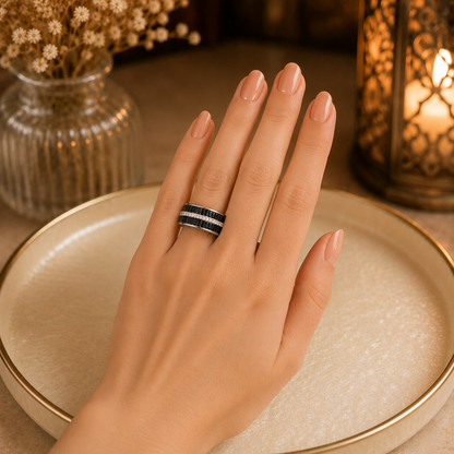 Model wearing a wide interwoven crystal band ring with sparkling zircon detailing on a manicured hand against a warm luxury setting