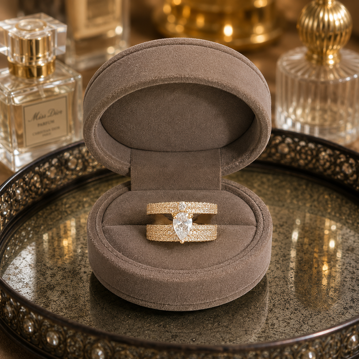 Light gold open-back double-band ring featuring a pear-cut clear centre stone with sparkling zircon detailing displayed in a luxury taupe velvet jewellery box.