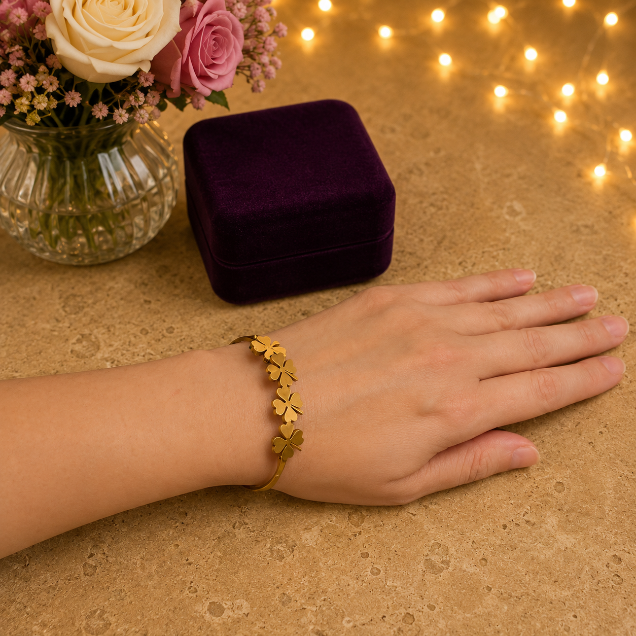 Woman wearing a gold four-leaf clover magnetic cuff bracelet with a luxury studio background featuring soft fairy lights.
