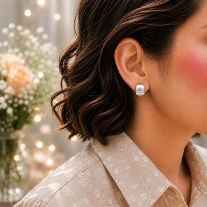 Matte silver mini huggie hoop earrings worn on model with brushed finish and modern minimalist style.