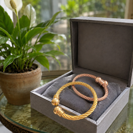 Gold and rose gold twisted cuff bracelets displayed together in a premium jewellery presentation box