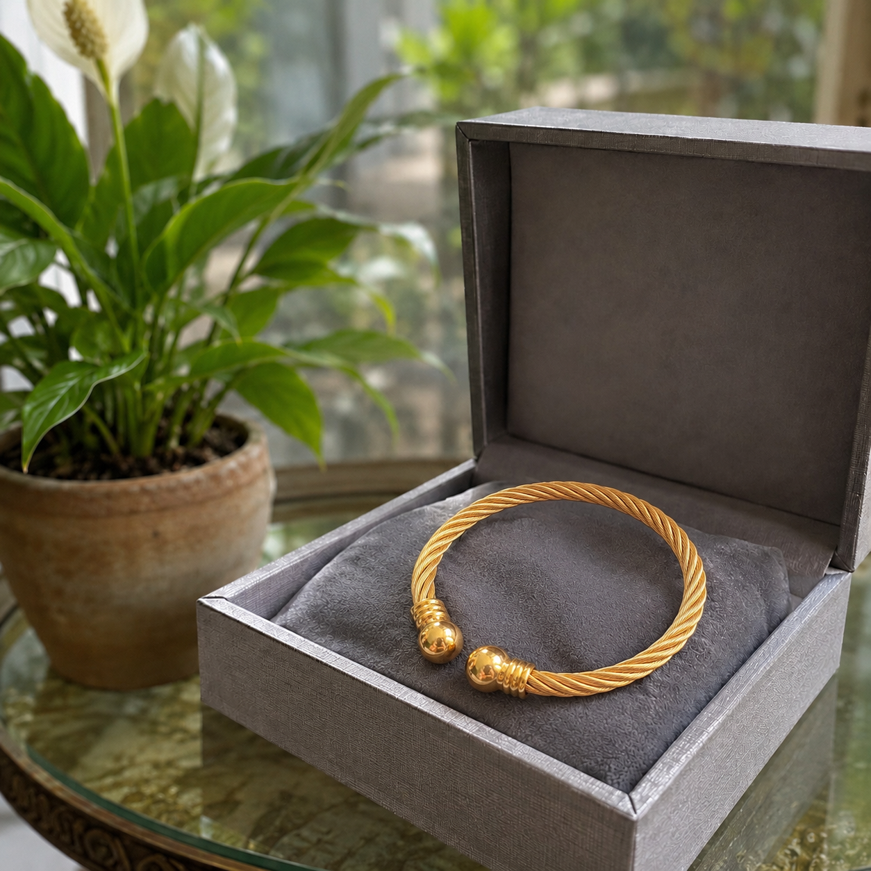 Gold twisted cable cuff bracelet displayed inside a luxury grey velvet jewellery box