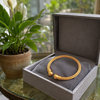 Gold twisted cable cuff bracelet displayed inside a luxury grey velvet jewellery box