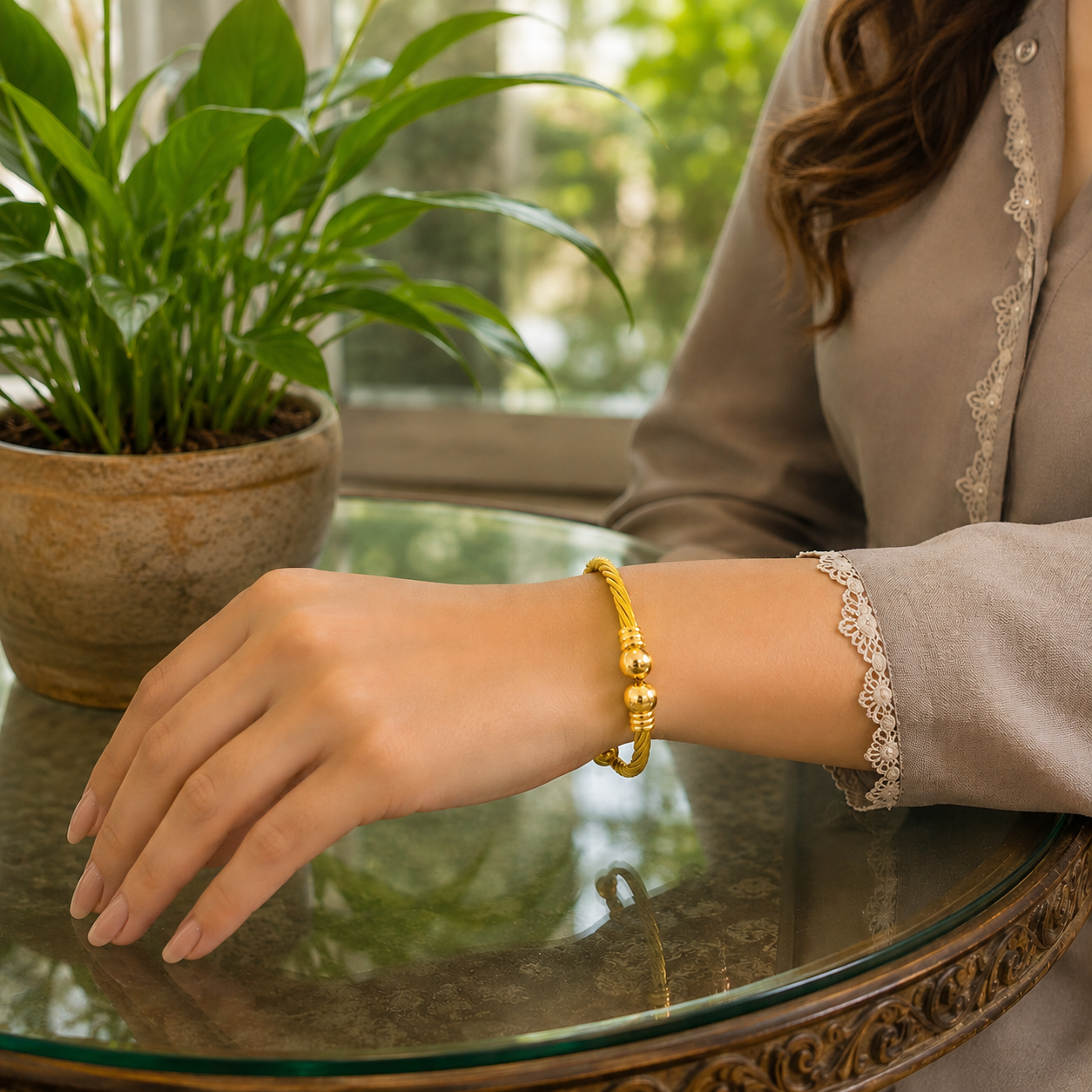 Gold twisted cable cuff bracelet worn on a model's wrist with natural daylight background