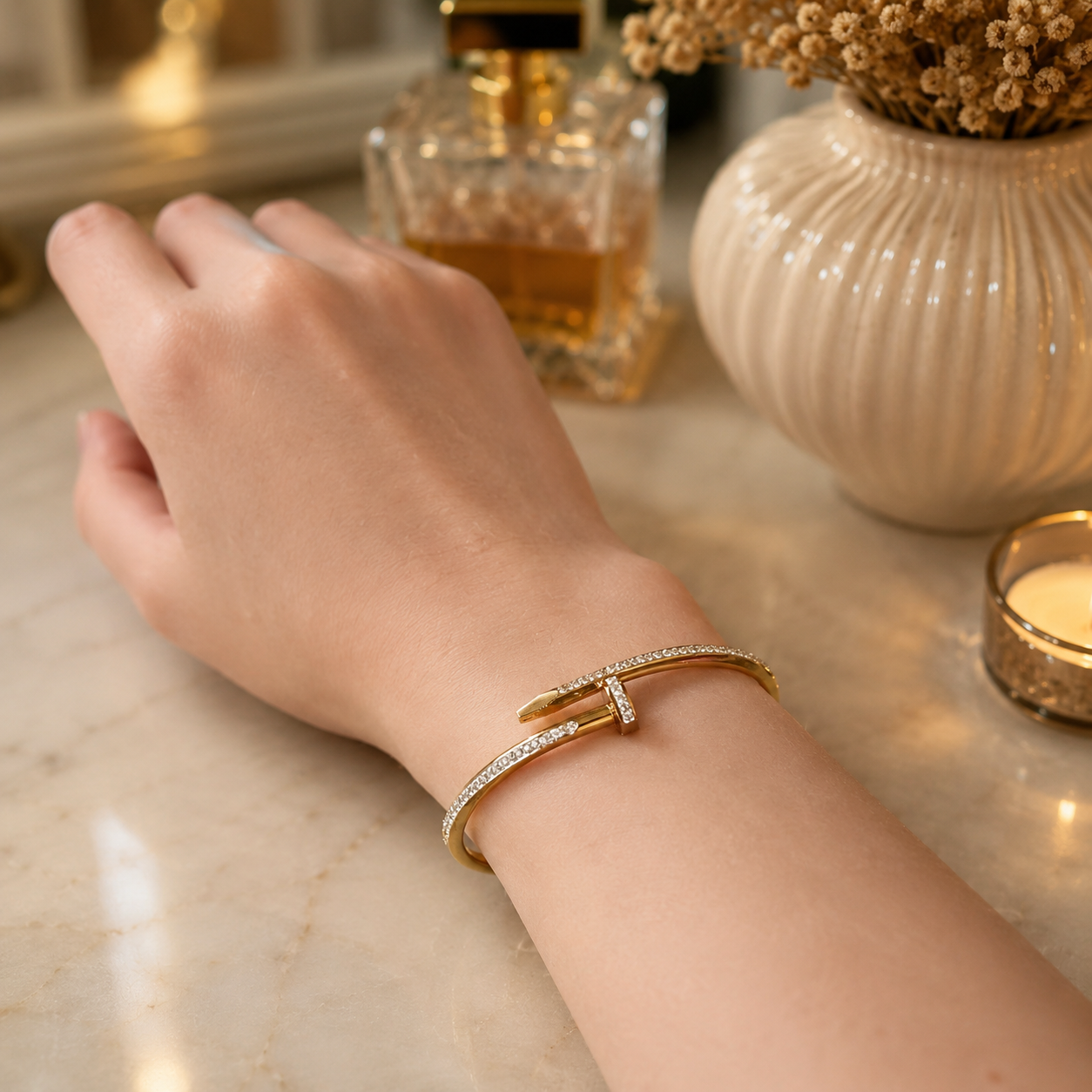 Elegant gold nail lock crystal cuff bracelet worn on a feminine wrist in a luxury lifestyle setting with warm ambient lighting.