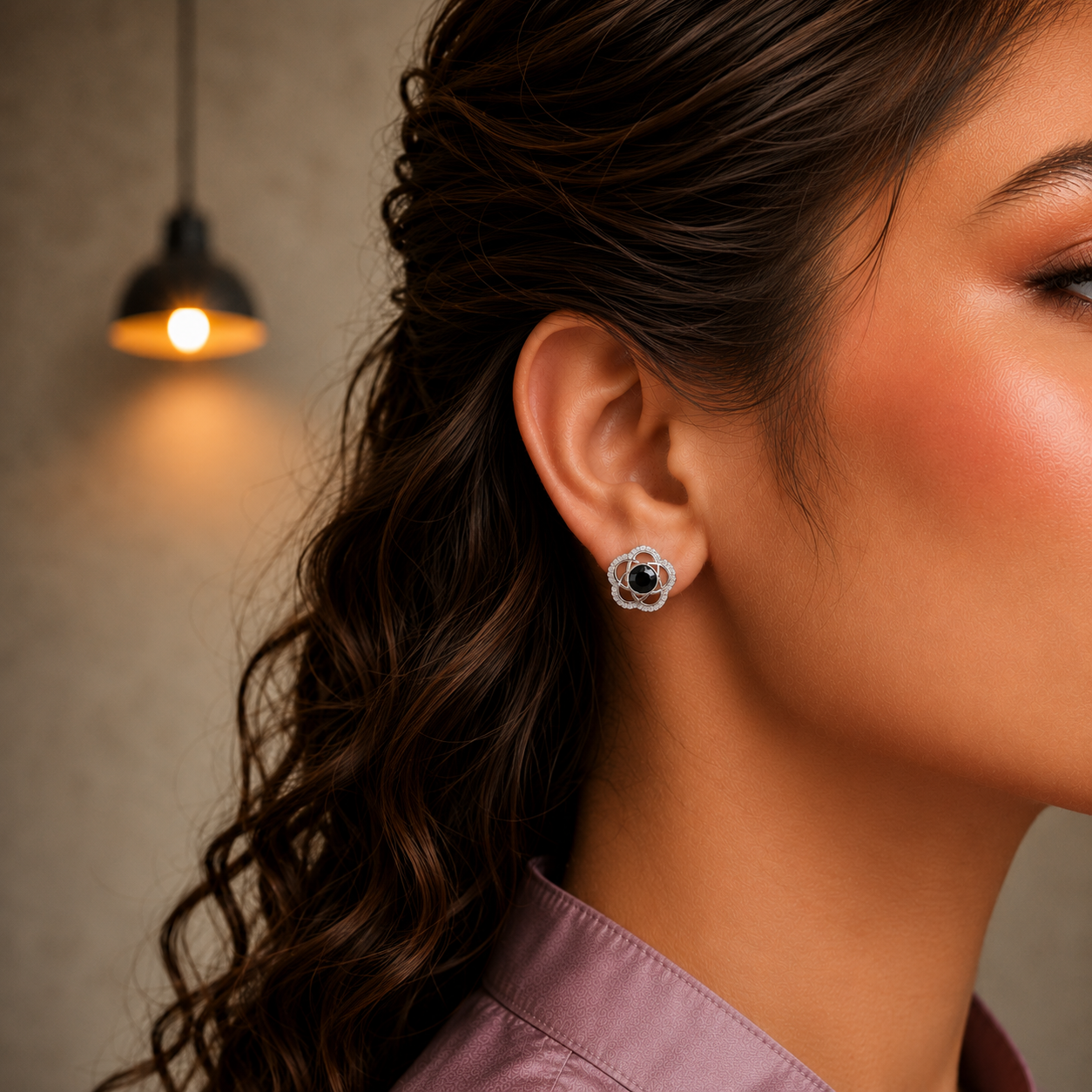 Close-up side profile of a model wearing silver floral stud earrings featuring black crystal center stones.