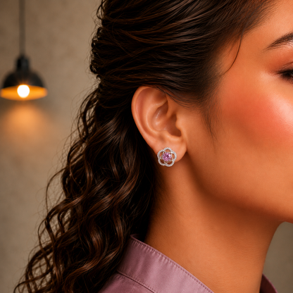Close-up side profile of a model wearing silver floral stud earrings featuring soft pink crystal center stones.