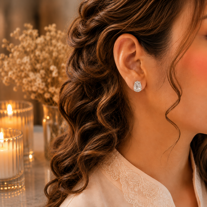 Woman wearing tulip crystal stud earrings in a luxury close-up portrait with soft curls, ivory-peach outfit, warm candlelight and dried floral background