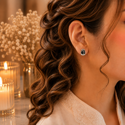 Woman wearing tulip crystal stud earrings in a luxury close-up portrait with soft curls, ivory-peach outfit, warm candlelight and dried floral background