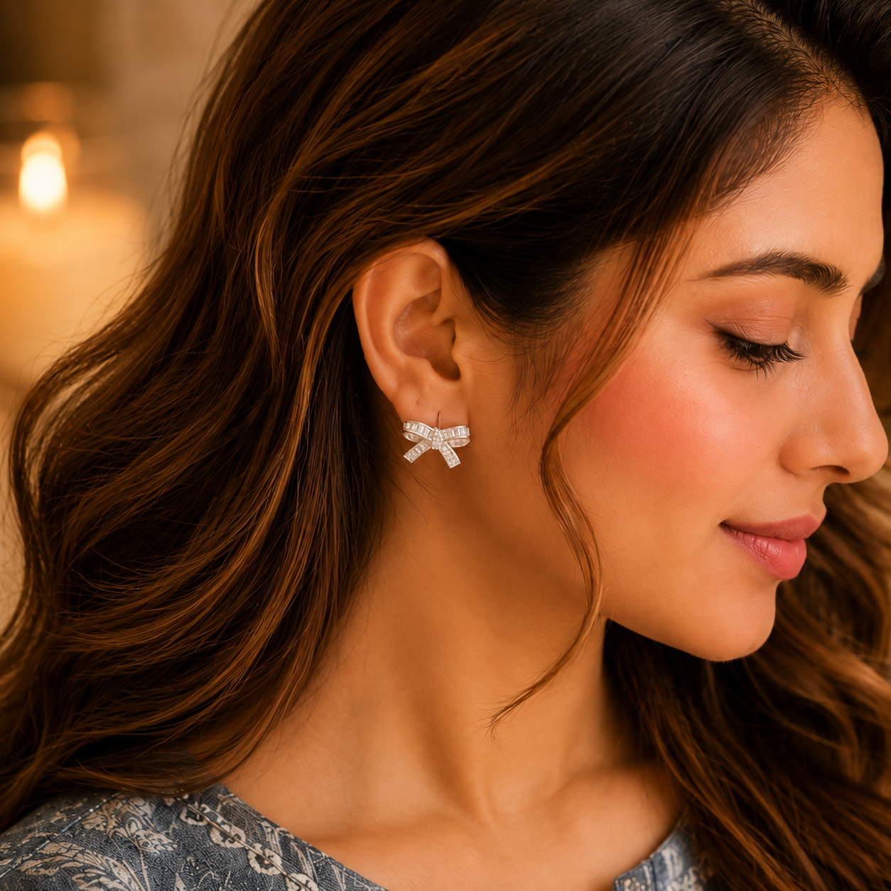 Close-up of a woman wearing silver crystal bow stud earrings with baguette zircon stones, styled with a smokey blue printed linen kurta in a luxury lifestyle setting.
