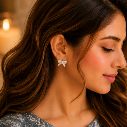 Close-up of a woman wearing silver crystal bow stud earrings with baguette zircon stones, styled with a smokey blue printed linen kurta in a luxury lifestyle setting.
