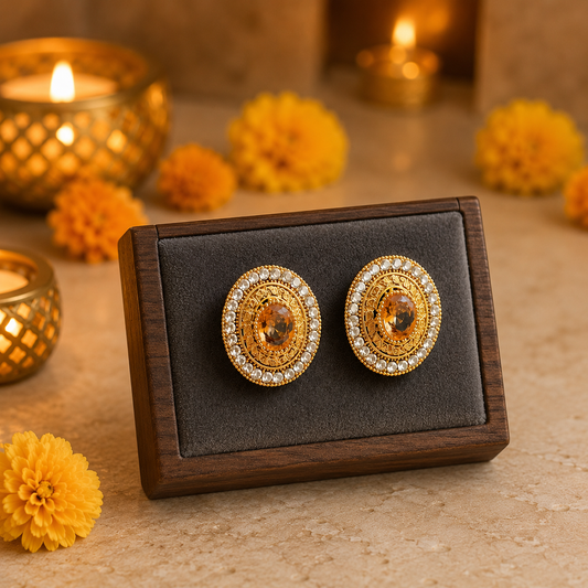 Golden halo stud earrings with champagne crystal centre displayed on a premium dark mocha velvet jewellery stand with warm candlelight background.