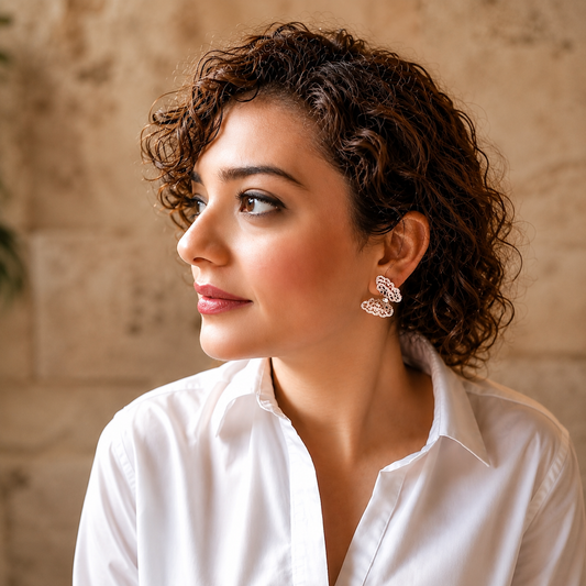 Woman wearing silver crystal butterfly statement earrings against a soft travertine stone background, showcasing the earrings' intricate baguette-cut crystal detailing and elegant sparkle.