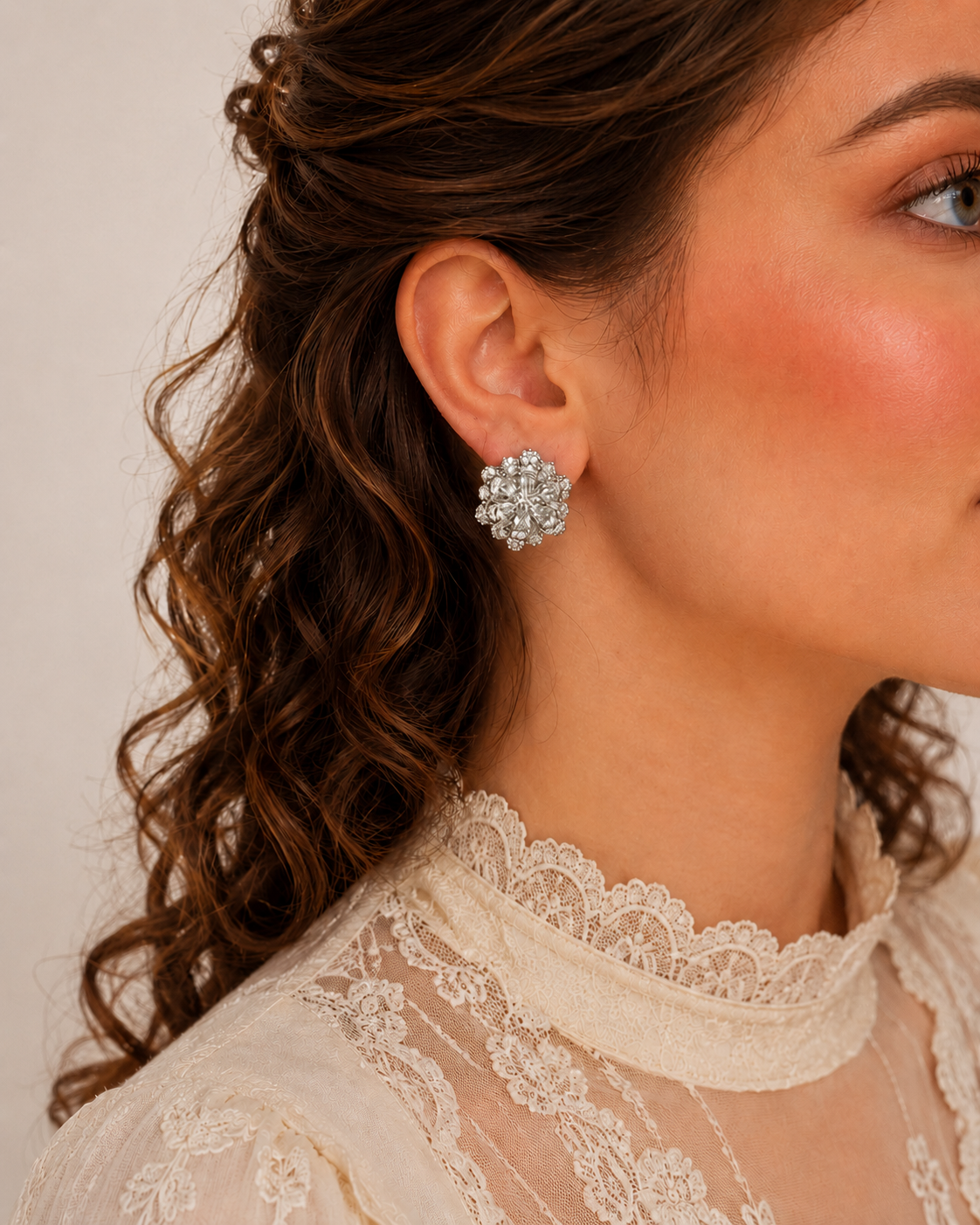 Silver floral crystal stud earrings worn by model with lace ivory blouse, sparkling flower design statement earrings close-up