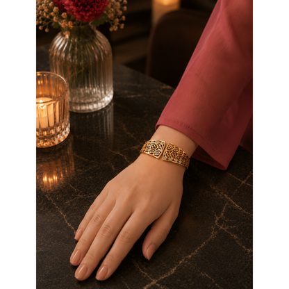 Woman wearing a gold botanical magnetic cuff bracelet with crystal detailing, styled on a luxury restaurant table with warm candlelight and elegant floral décor.