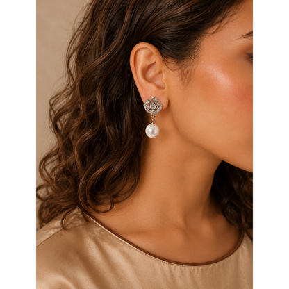 Model wearing silver floral pearl drop earrings featuring crystal accents and a lustrous pearl, styled with a champagne gold silk top.