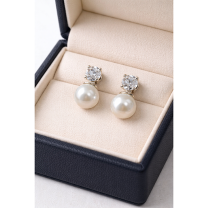 Silver pearl and zircon drop earrings displayed in cream velvet jewelry box with warm reflective shine
