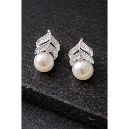  Silver leaf-design pearl zircon stud earrings displayed on black stone surface in high-definition