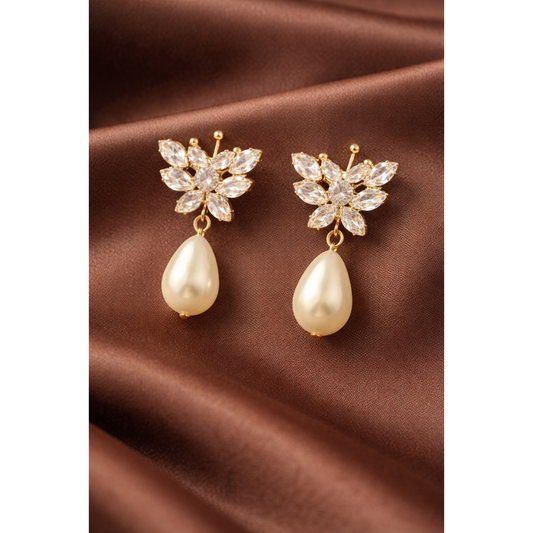 Gold butterfly crystal pearl drop earrings styled on satin cloth showing crystal wing detail and smooth pearl drops