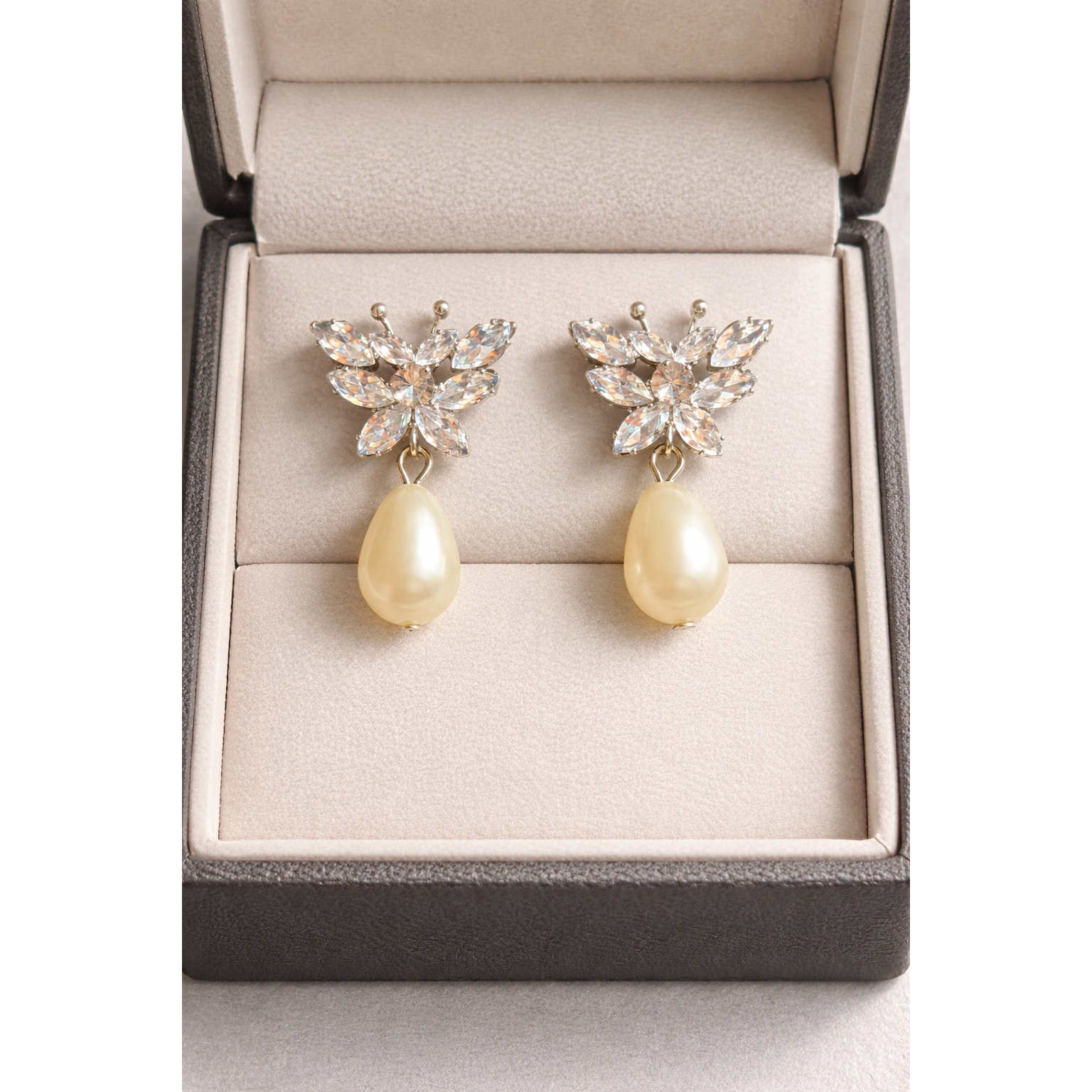 Silver butterfly crystal pearl drop earrings placed in a luxury jewelry box with studio lighting and sharp product detail