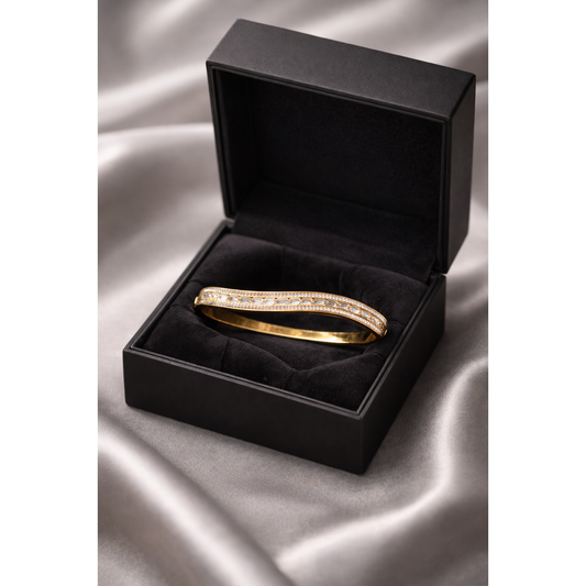 Gold-tone crystal bracelet with lock clasp displayed in black velvet jewelry box on grey satin