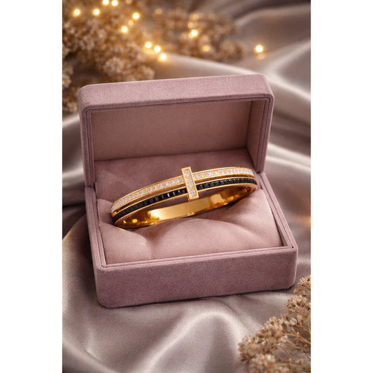 Gold crystal and black stone lock bracelet displayed inside mauve velvet jewelry box on satin grey fabric with fairy lights
