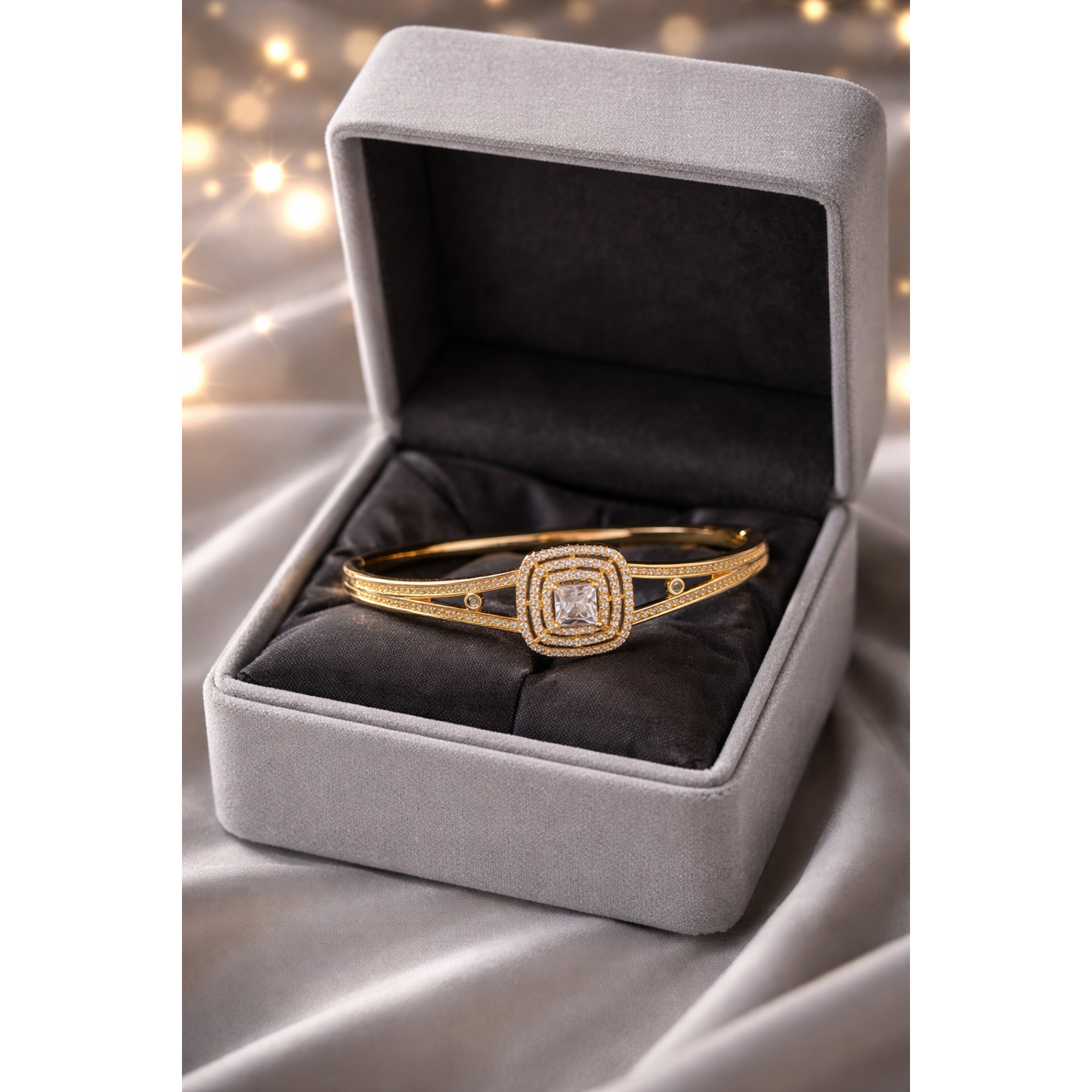 Gold lock bracelet with princess cut center stone and pavé halo design inside premium grey velvet box with soft bokeh background