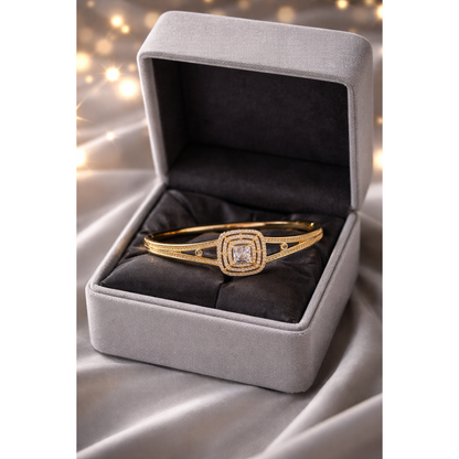 Gold lock bracelet with princess cut center stone and pavé halo design inside premium grey velvet box with soft bokeh background