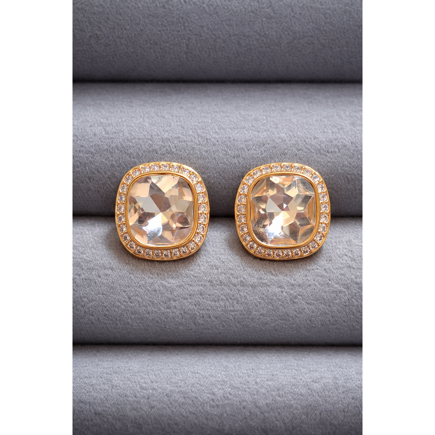 Pair of gold cushion-cut champagne crystal stud earrings with halo border displayed on grey velvet.