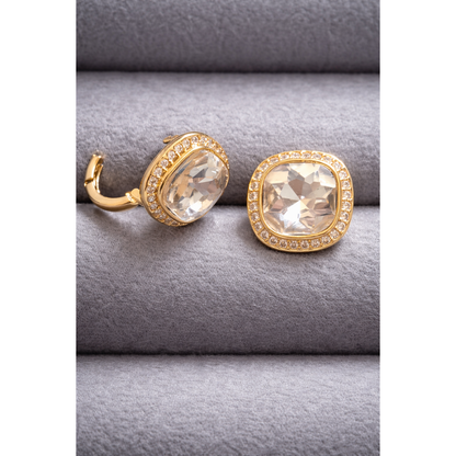 Gold cushion-cut champagne crystal stud with halo detailing shown in side and front view on grey velvet background.
