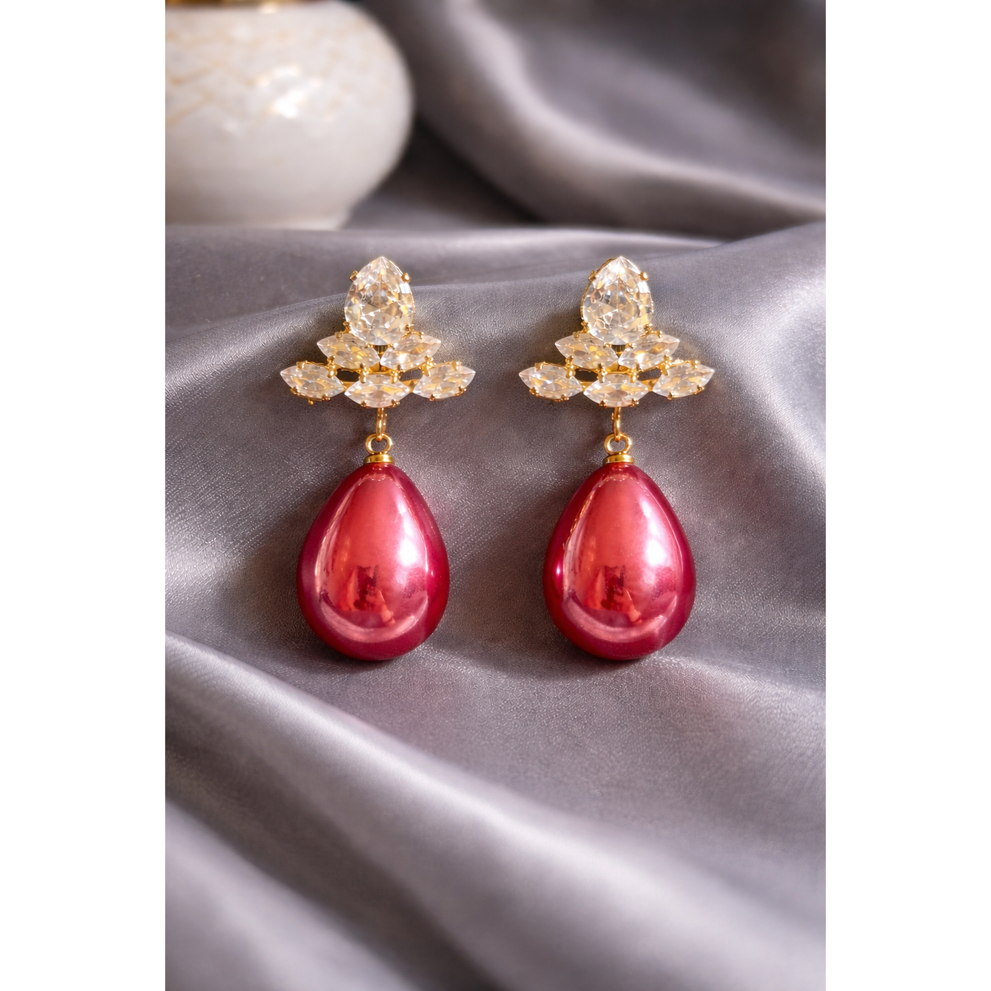 Plum rose teardrop crystal earrings displayed on grey satin with gold-tone crystal cluster