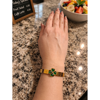 Gold clover bracelet with green stones worn on wrist on café counter