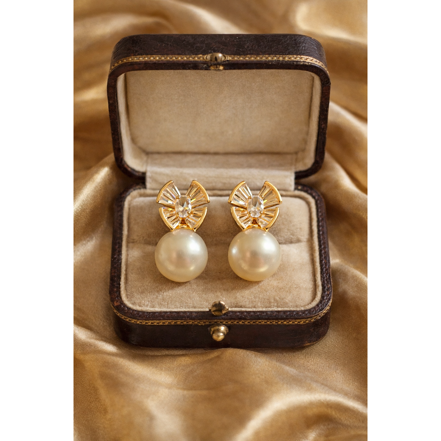 Pearl drop crystal earrings showcased in a vintage  jewellery box placed on golden satin fabric