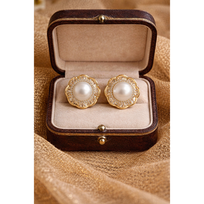 Gold pearl halo stud earrings displayed in antique wooden jewelry box on golden net cloth