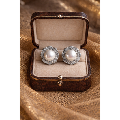 Silver pearl halo stud earrings displayed in antique wooden jewelry box on golden net cloth