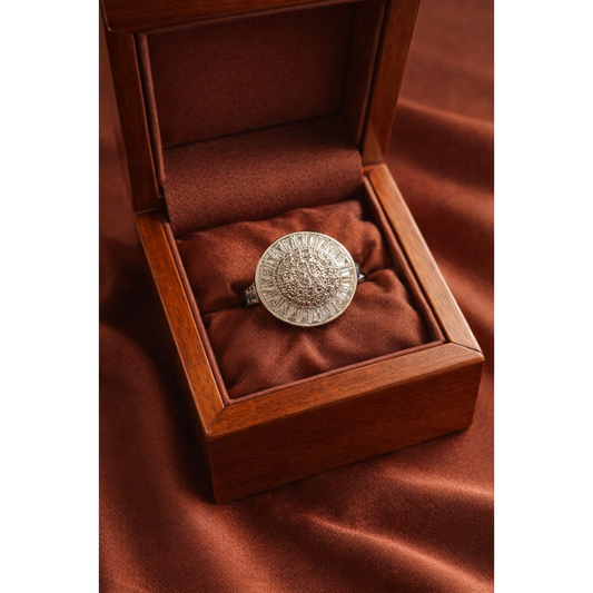 Silver halo statement ring with pavé dome center and baguette-cut stone frame displayed in a wooden jewelry box on rust satin background.