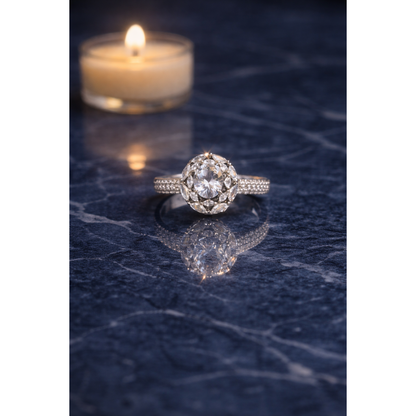 Silver round halo ring placed on navy blue marble surface with blurred candlelight and soft reflection