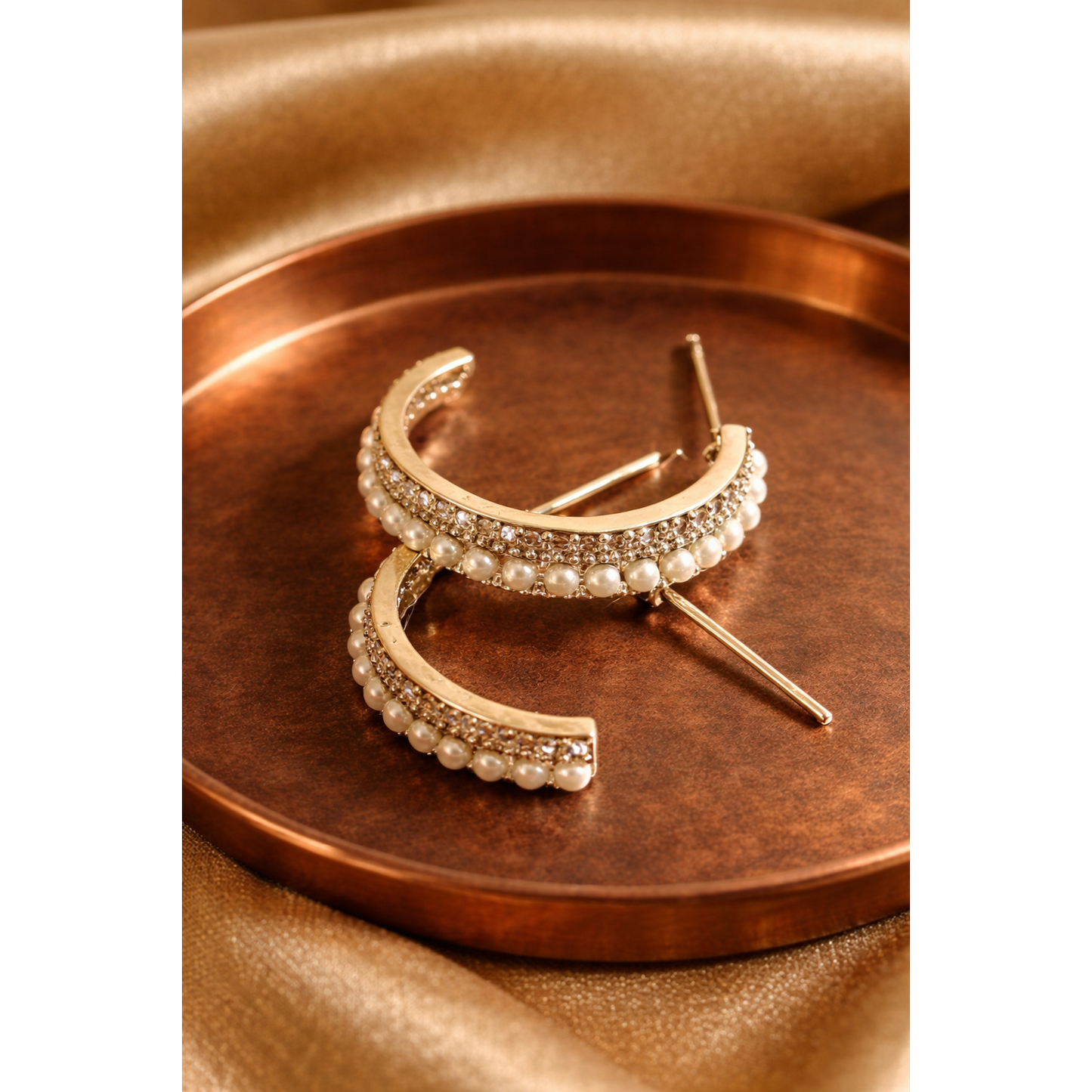 Gold hoop earrings with pearl accents on a bronze tray