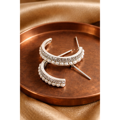 Silver hoop earrings with pearl accents on a bronze tray