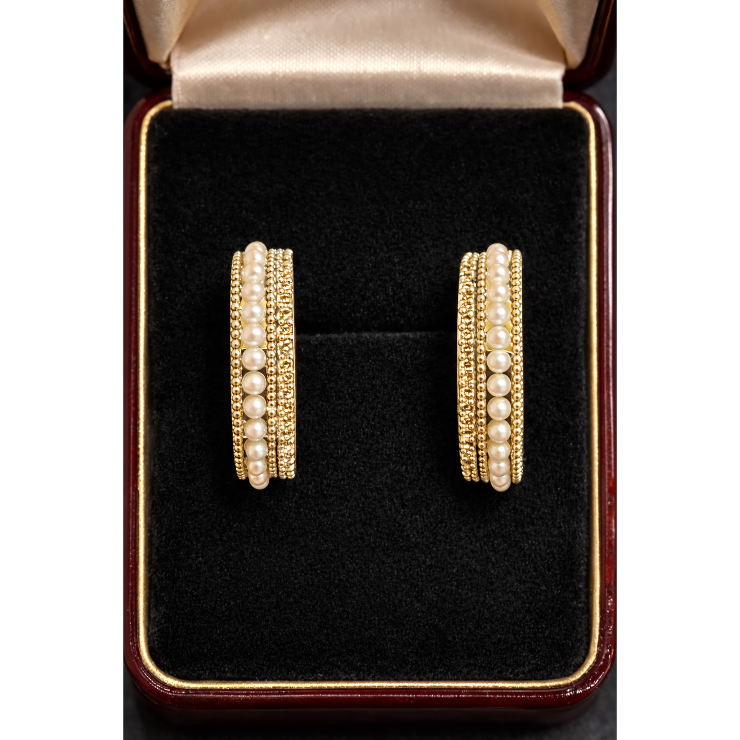 Pair of gold pearl row multi-band hoop earrings displayed inside a black velvet jewelry box showing layered design and beadwork texture