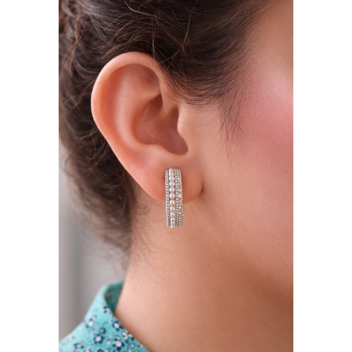 Close side profile of a woman wearing silver pearl row multi-band hoop earrings with detailed 