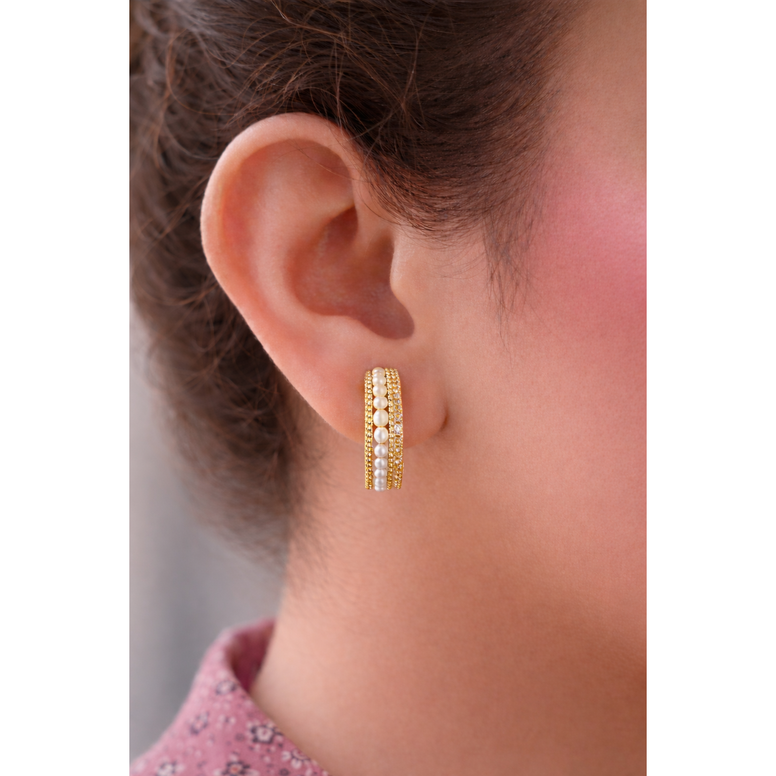 Close side profile of a woman wearing Gold pearl row multi-band hoop earrings with detailed beadwork